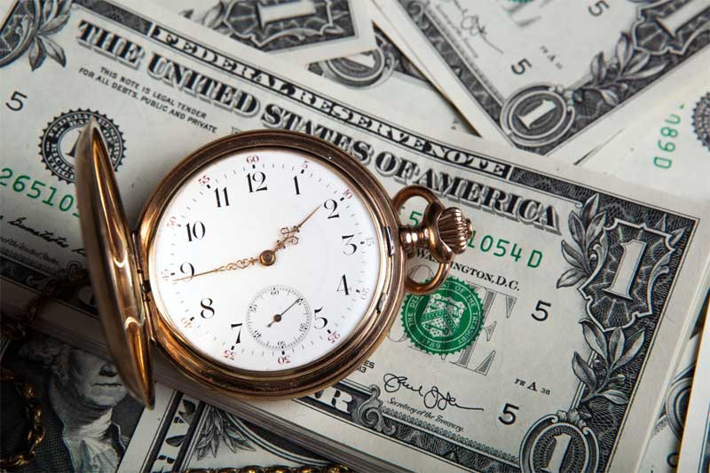 Pocket Watch Laying on Top of One-Dollar Bills